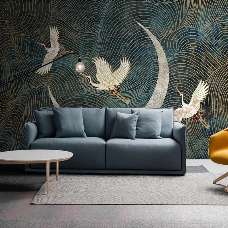 Blauwe sofa met kussens voor een artistieke muurschildering met vliegende kraanvogels en een maansikkel.